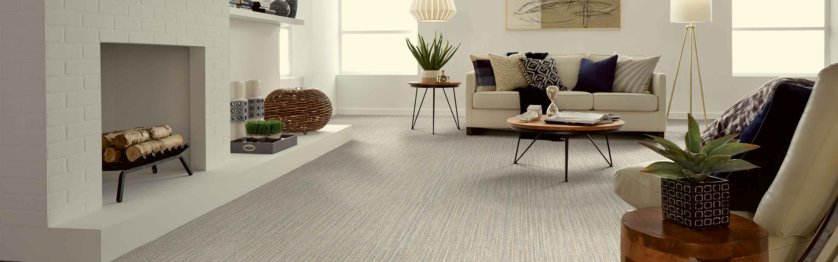 gray patterned carpet in coastal living room with white brick fireplace, neutral furniture and wood accents