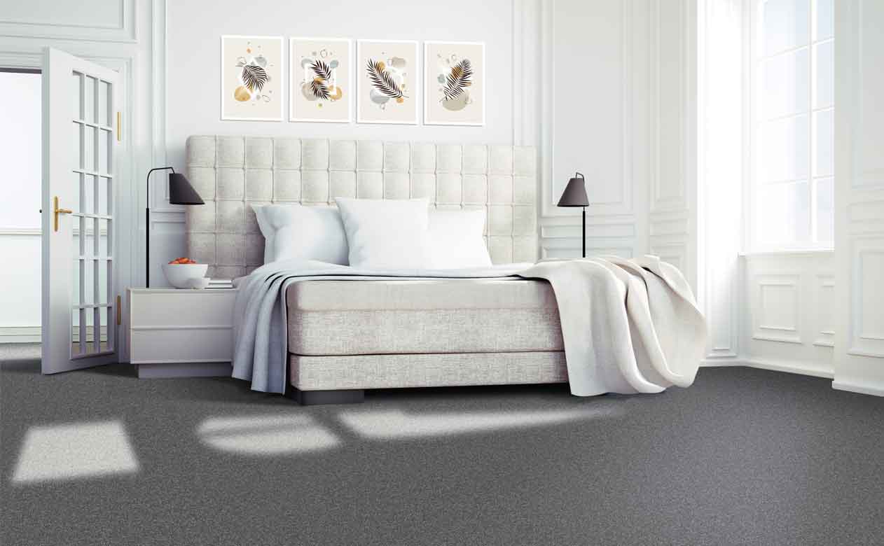 Dark grey carpet in bedroom with cream fabric bedframe and light bedsheets