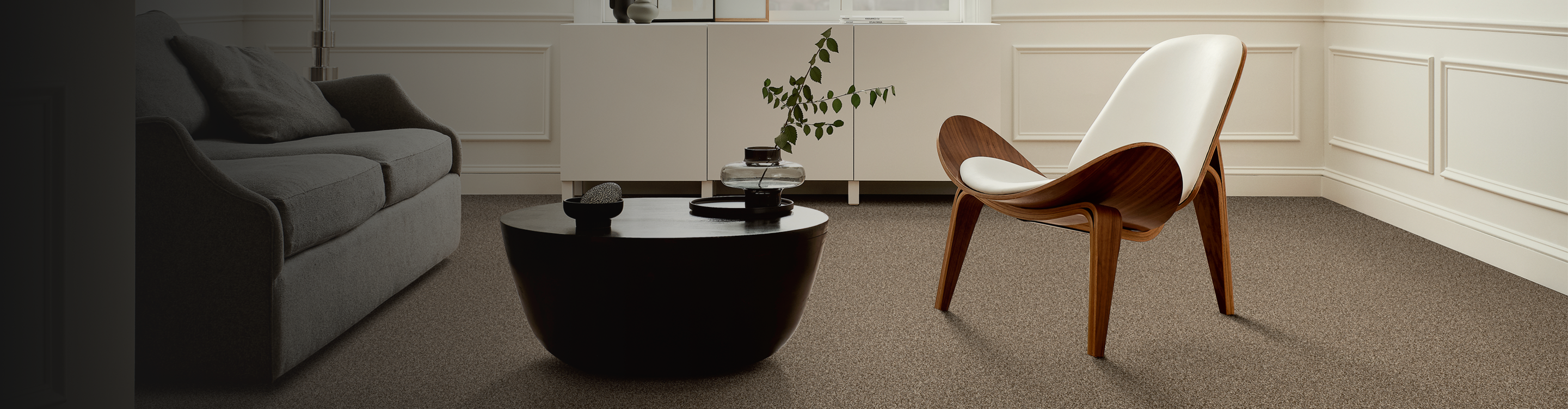 beige neutral carpet in contemporary living area gray couch, black coffee table and white modern chair